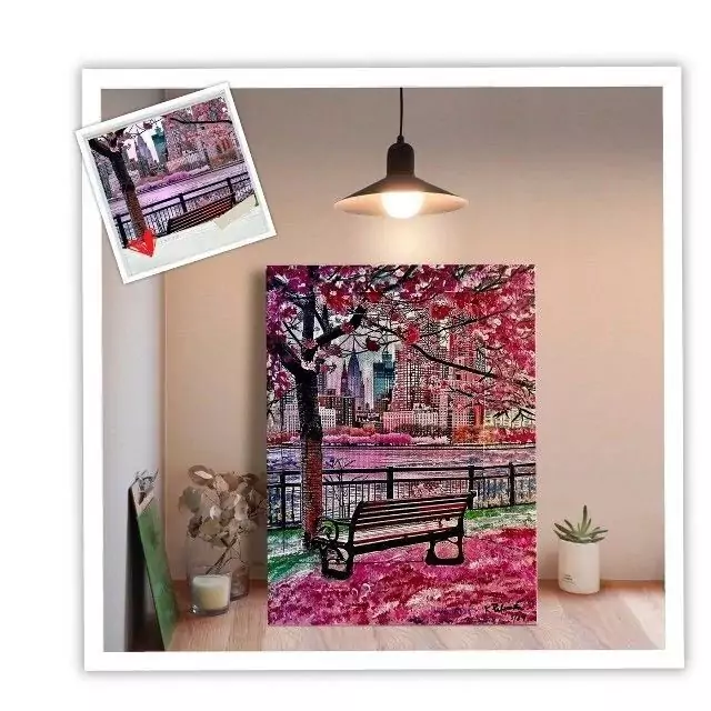 Colorful artwork of a park scene with cherry blossoms and a bench, displayed in a cozy interior setting, highlighting urban beauty.
